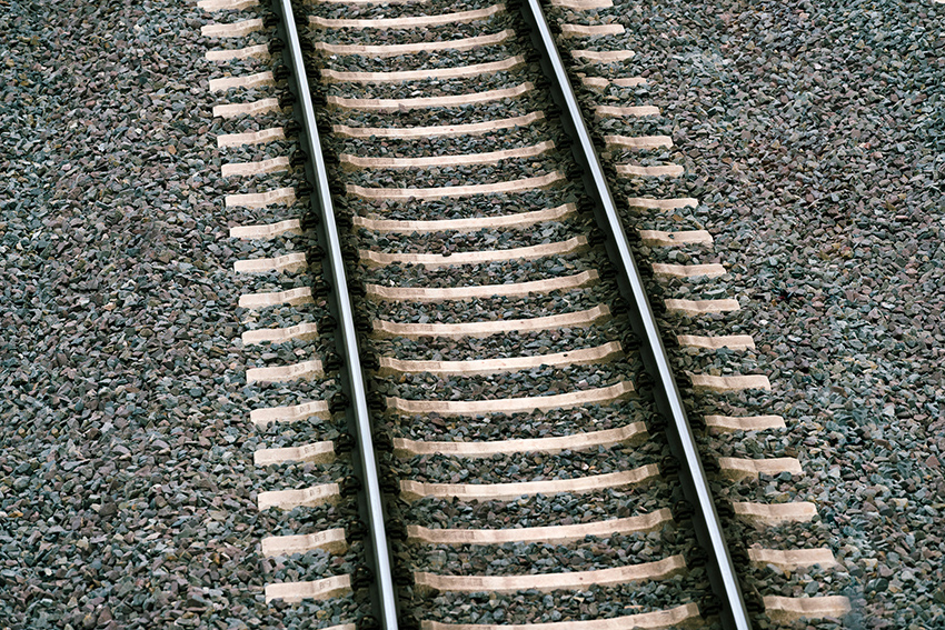 Nahaufnahme eines Eisenbahngleises mit Schotterbett aus der Vogelperspektive.