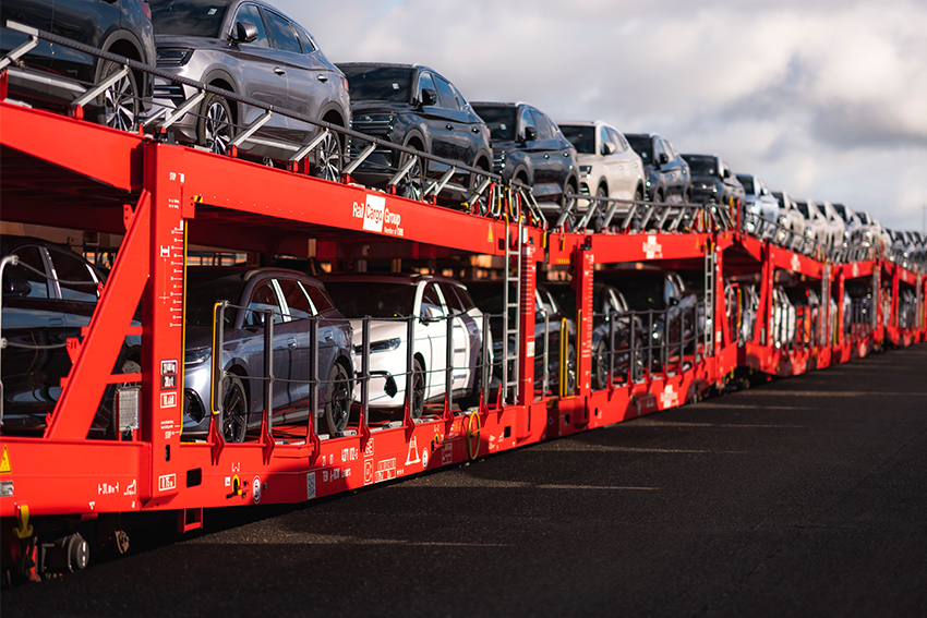 Autos auf einem roten RCG Autotransportwagen für den Schienentransport.