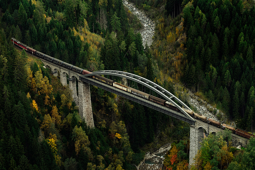 Güterzug überquert Brücke in einem Tal